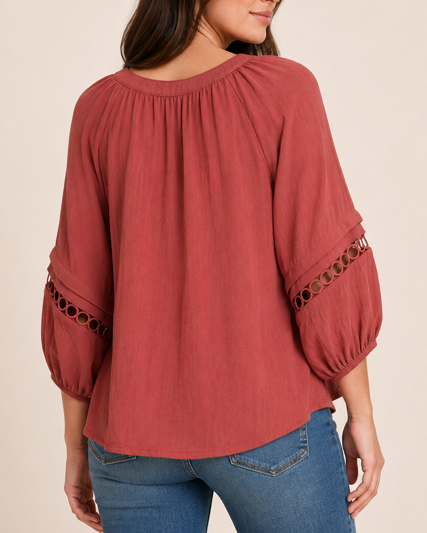 Back view of a woman wearing a warm rust-red textured knit top with balloon sleeves on a beige background