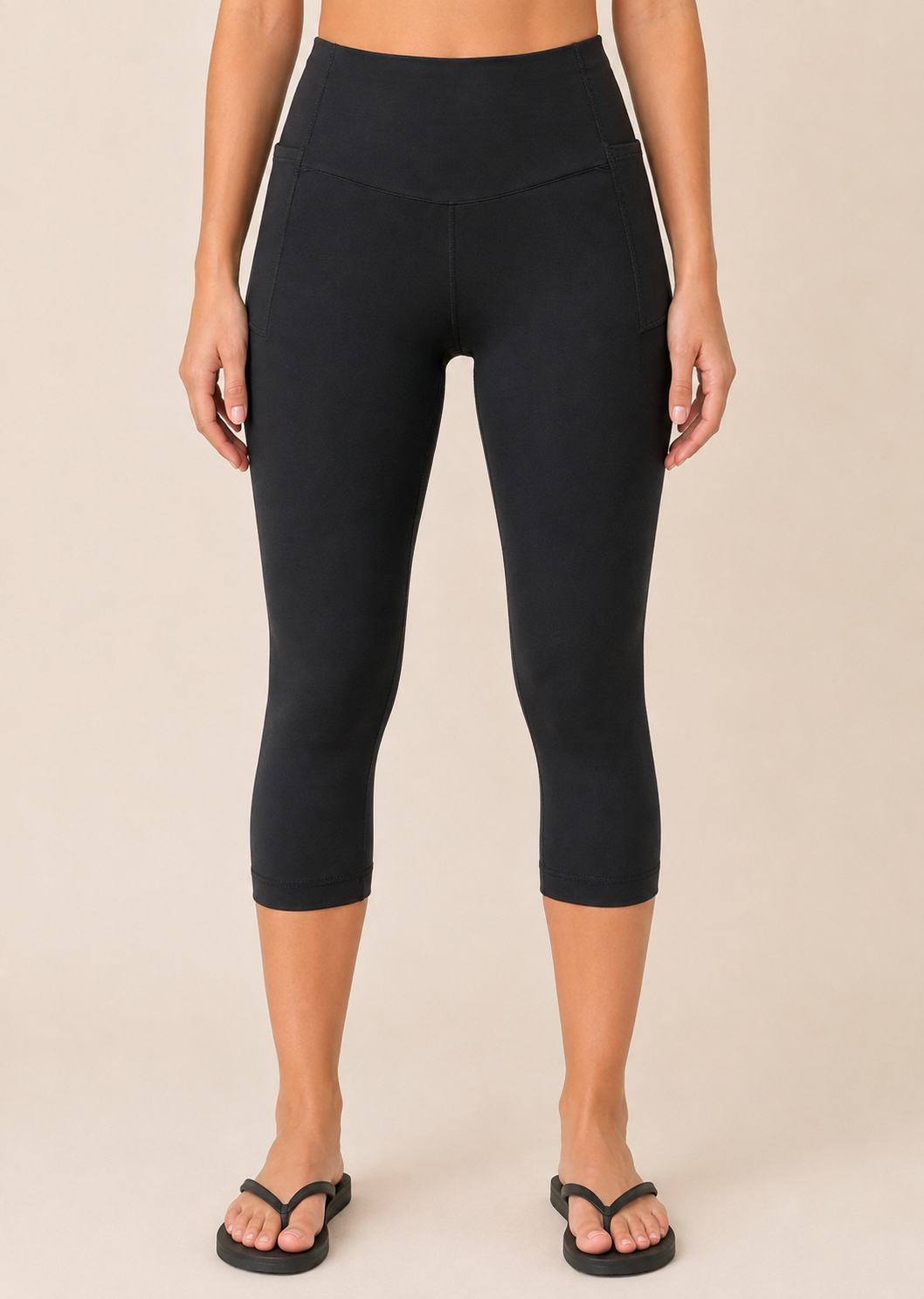 Close-up view of black capri leggings with pockets on a beige background