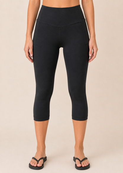 Close-up view of black capri leggings with pockets on a beige background