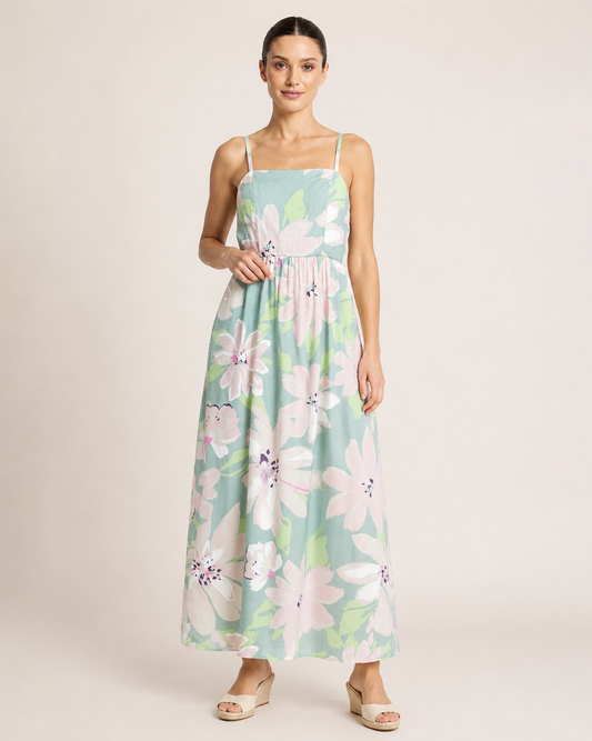 Full-body view of a woman wearing a pastel floral maxi dress and beige sandals on a beige background