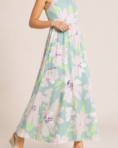 Side view of a woman wearing a pastel floral maxi dress and beige sandals on a beige background