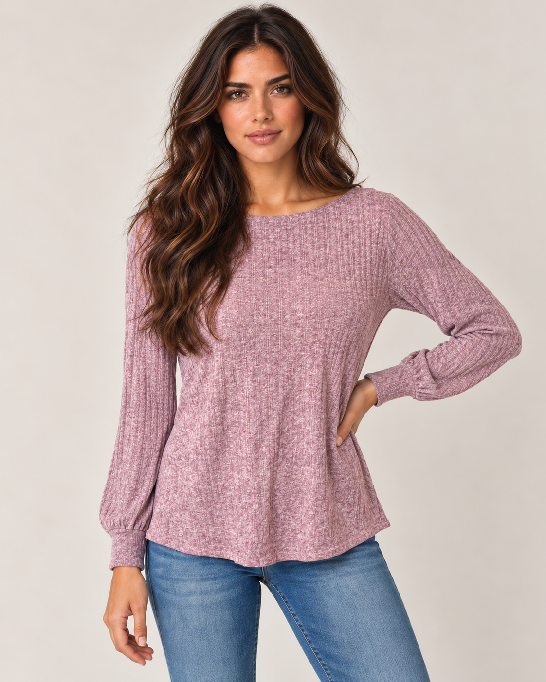 Cropped front view of a woman wearing a dusty mauve lightweight crewneck sweater with long sleeves and blue jeans on a beige background.
