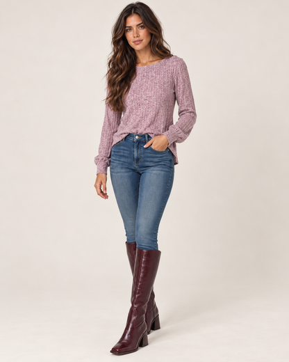 Side view of a woman wearing a dusty mauve lightweight crewneck sweater with long sleeves and blue jeans on a beige background.
