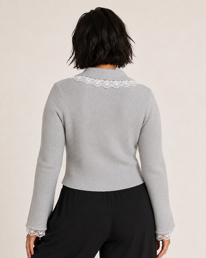 Back view of a woman wearing a gray lace detail flare sleeve knit cardigan with black pants on a beige background