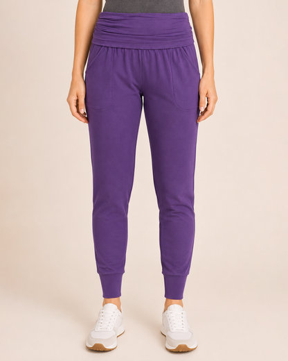 Close-up view of eggplant foldover waist joggers on a beige background