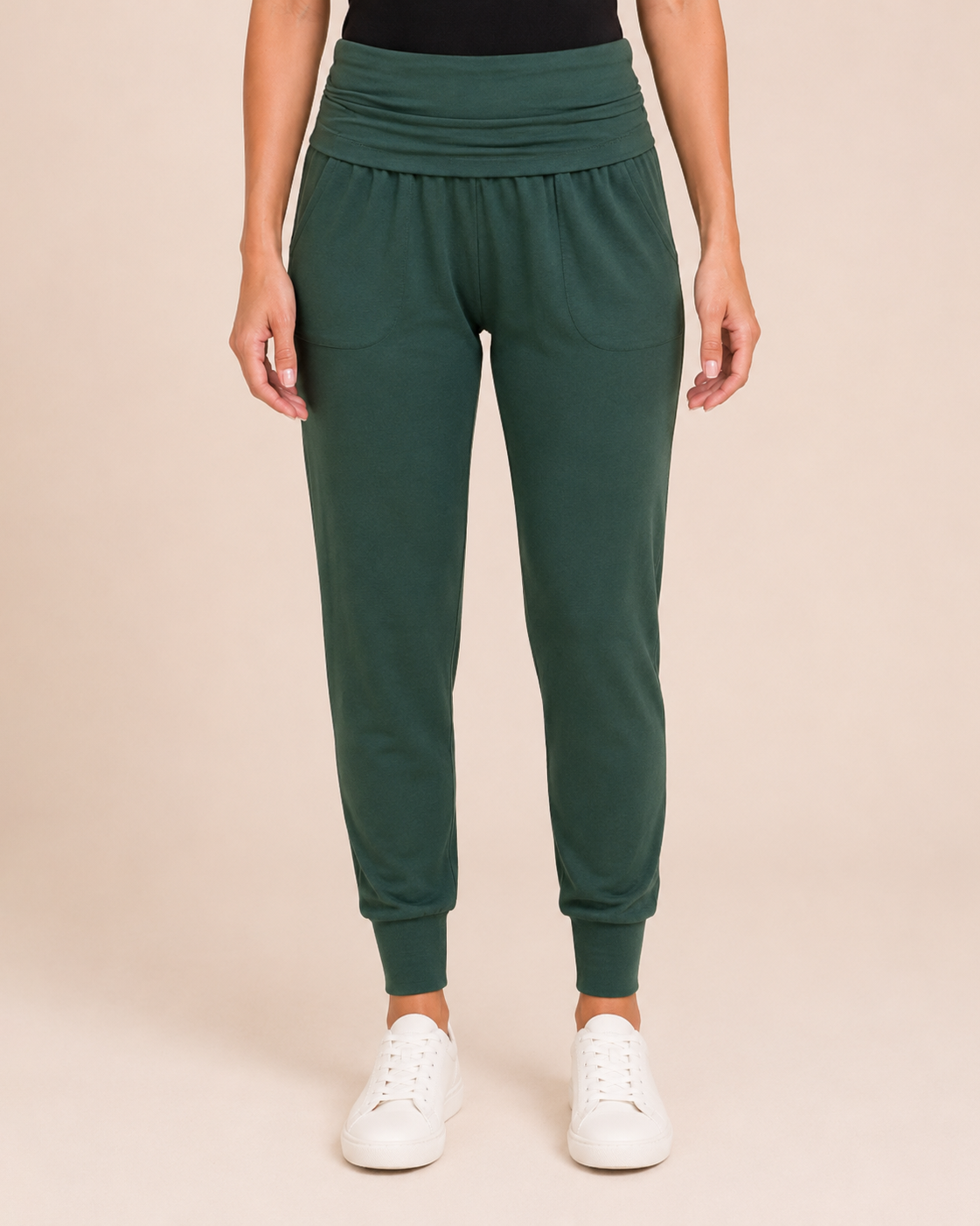 Close-up view of hunter green foldover waist joggers on a beige background