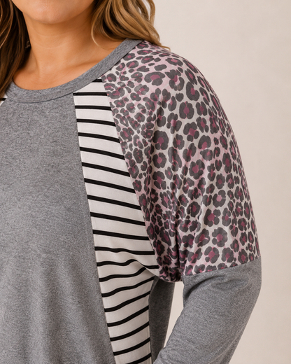 Close-up of the mixed print detail on a gray oversized dolman sleeve tunic on a beige background