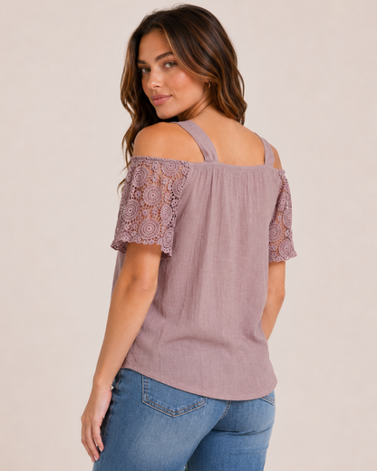Back view of a woman wearing a mauve cold shoulder lace blouse and cropped blue jeans on a beige background