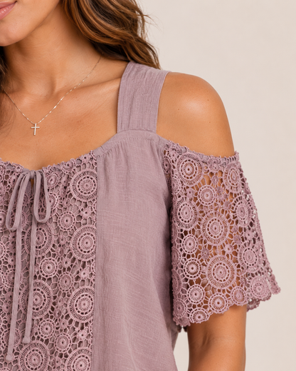 Close-up of a woman wearing a mauve cold shoulder lace blouse on a beige background
