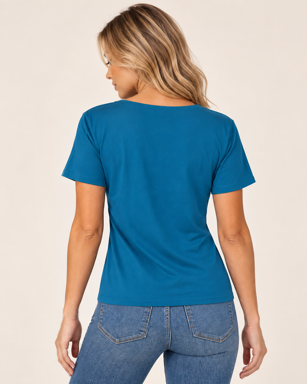 Back view of a woman wearing a teal blue square-neck short-sleeve fitted top on a beige background.